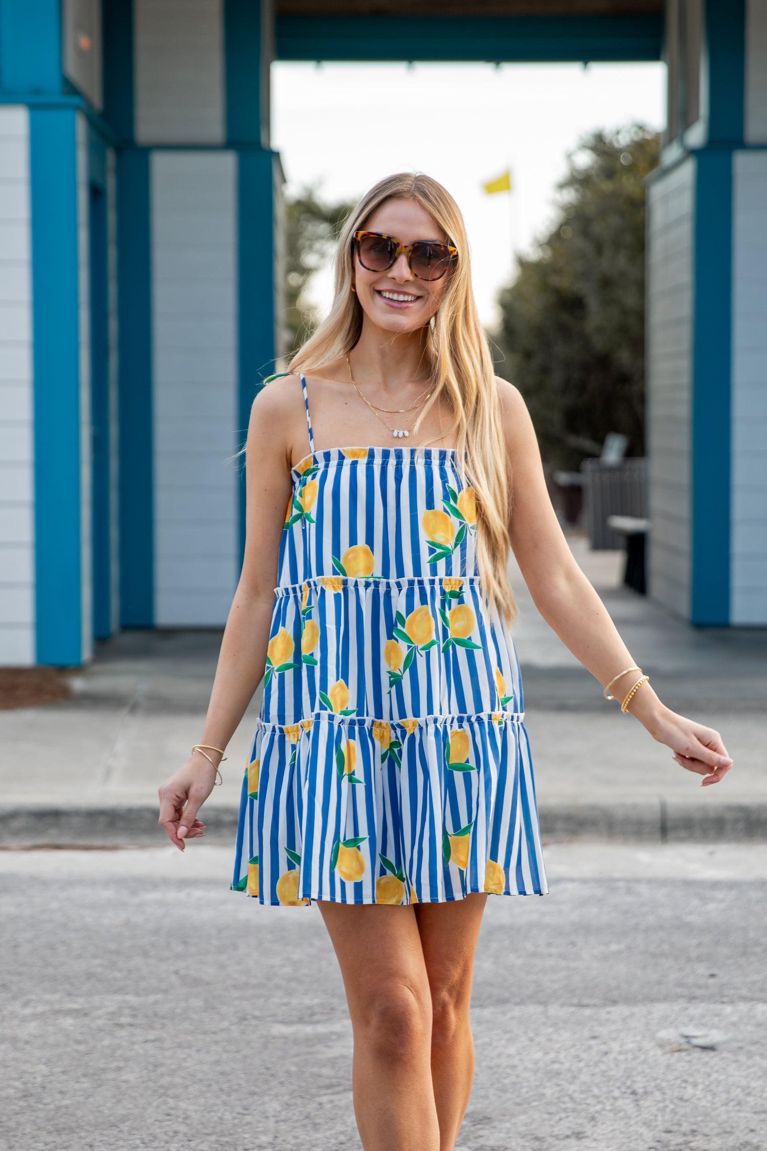 Woman wearing a blue and white striped dress with lemon pattern outdoors.