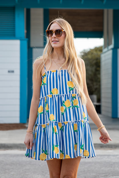 Woman wearing a blue and white striped dress with lemon pattern outdoors.