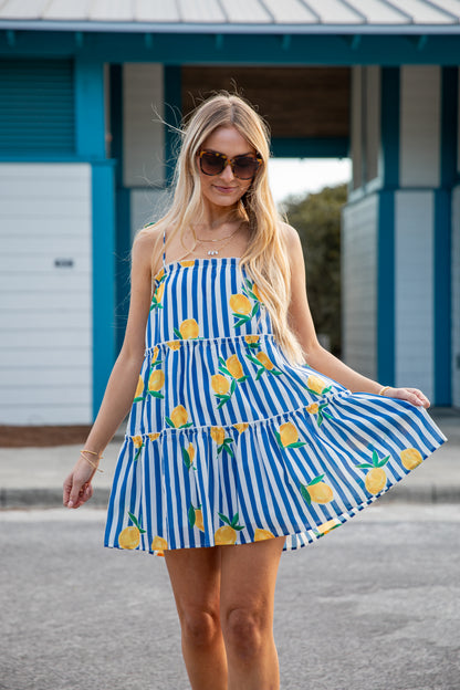 Woman wearing a blue and white striped dress with pineapple patterns outdoors.