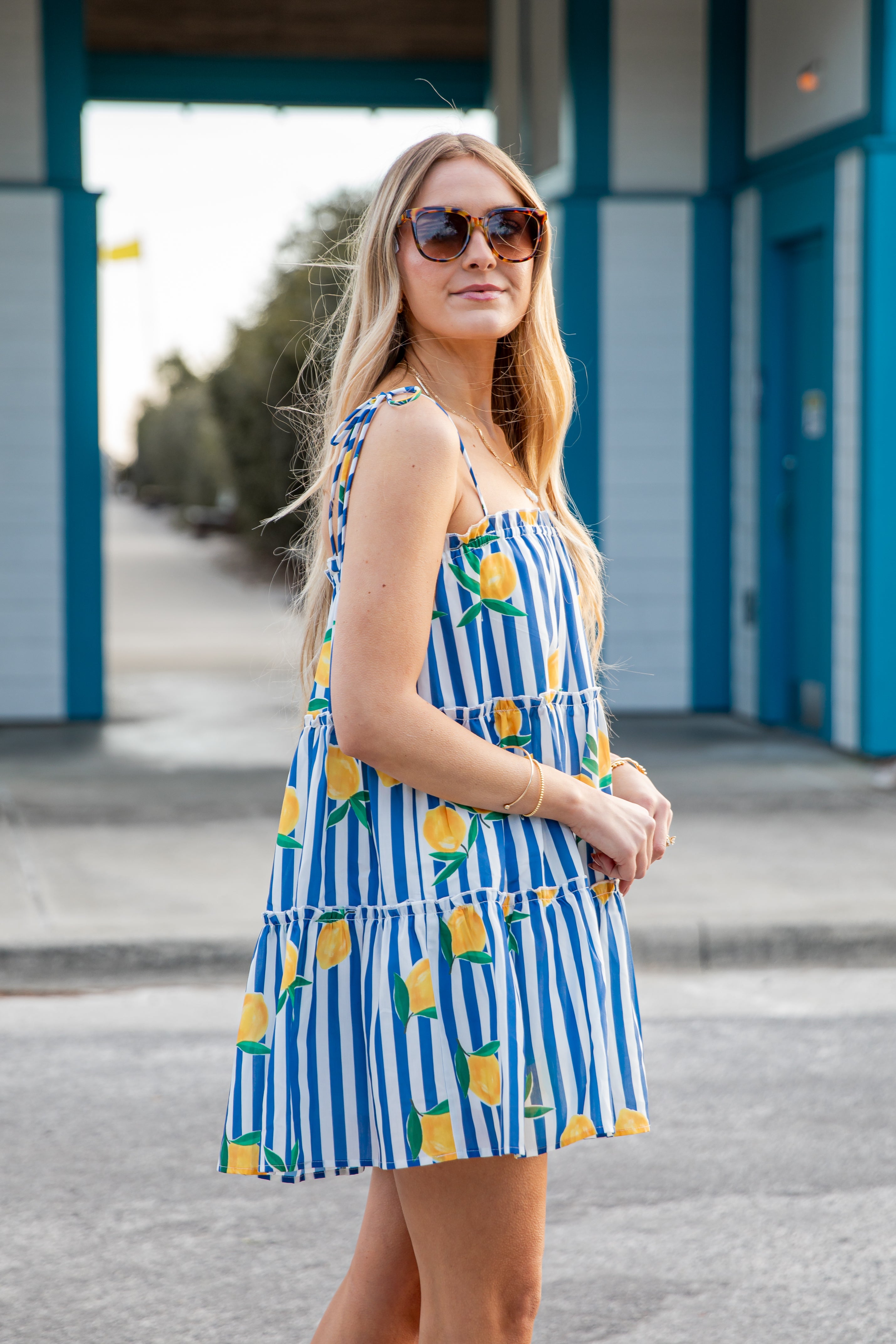 Woman wearing a blue and white striped dress with pineapple pattern outdoors.