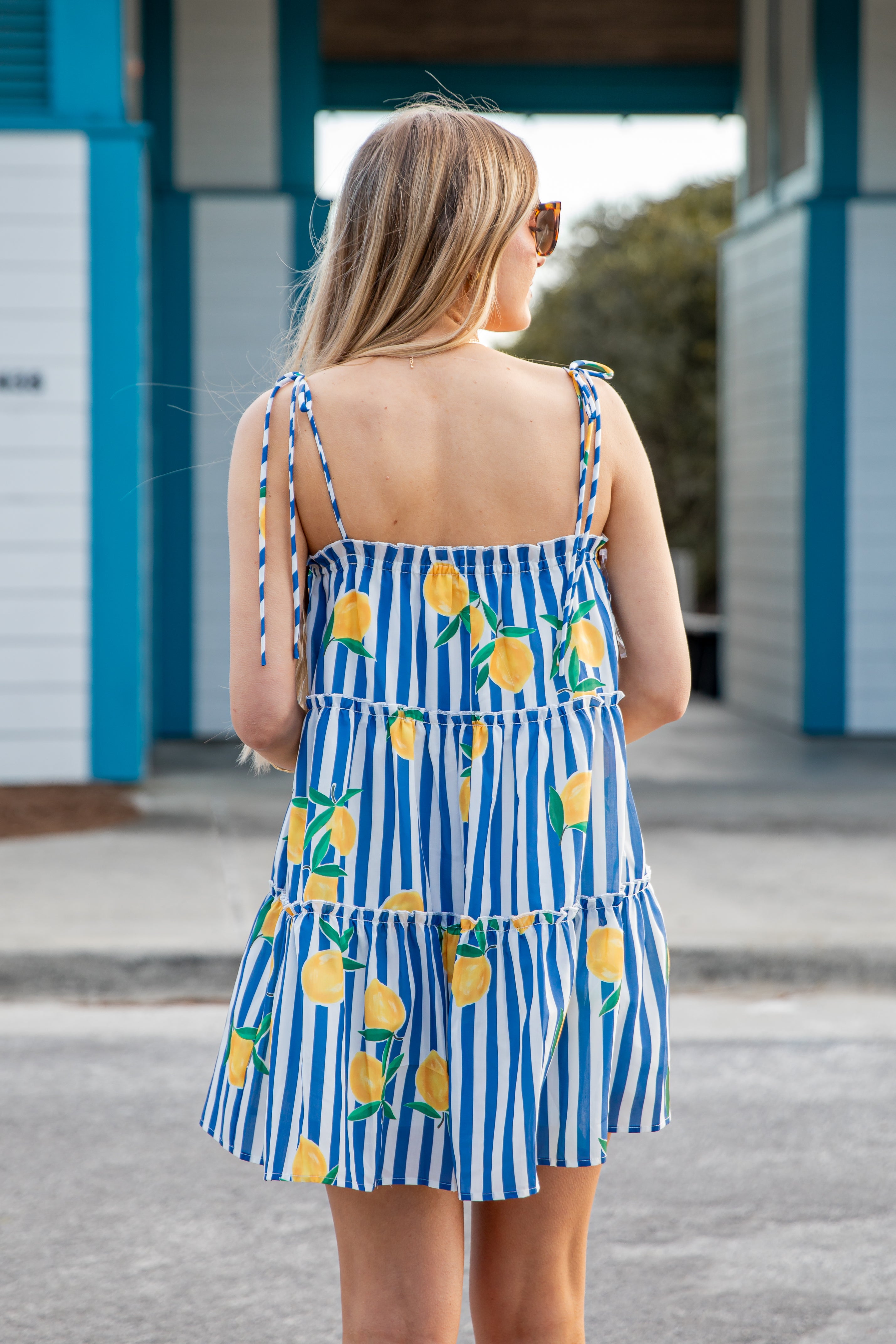 Woman wearing a blue and white striped dress with lemon pattern outdoors.