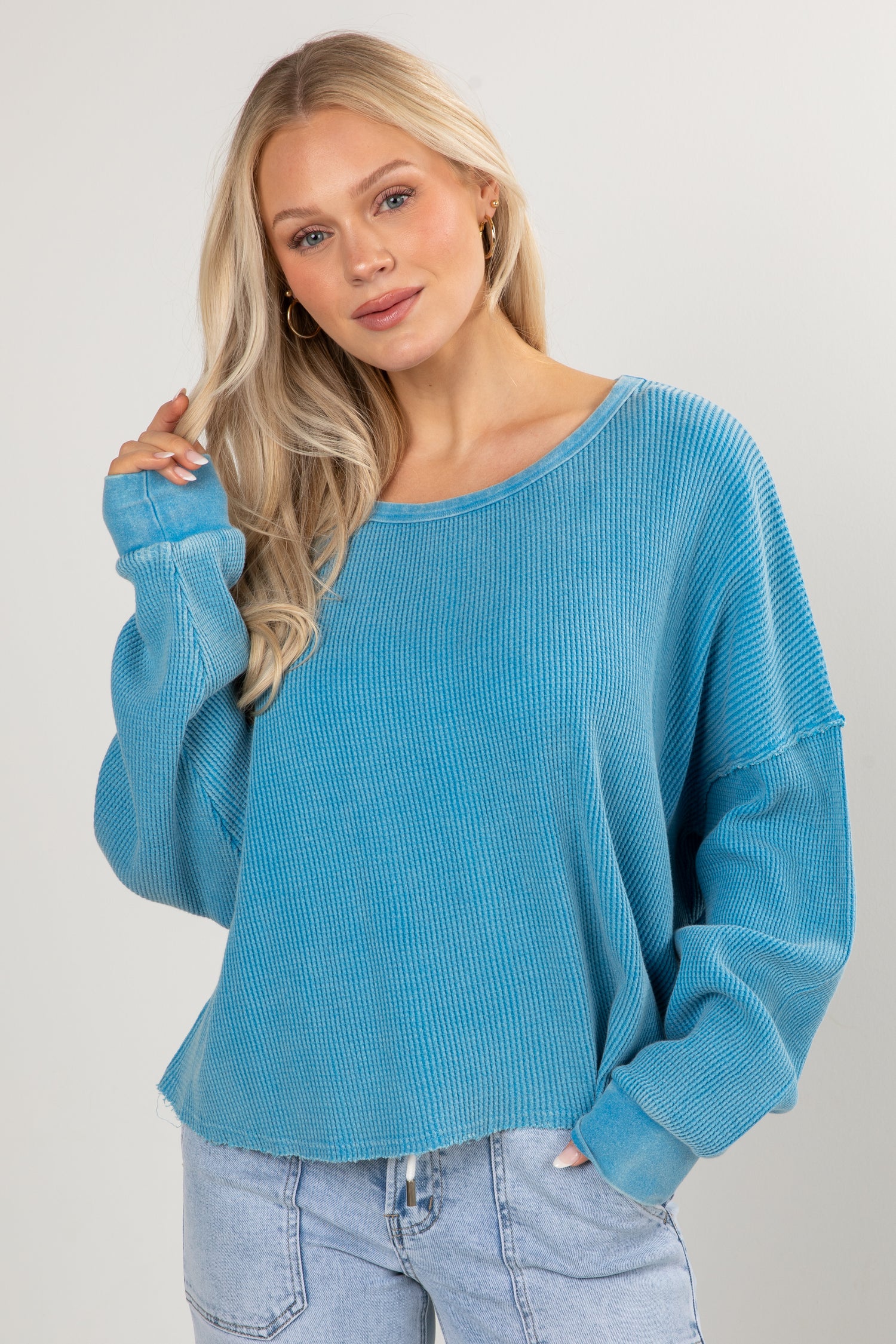 Woman wearing a blue sweater and jeans against a plain background