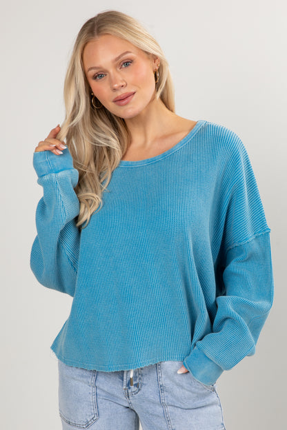 Woman wearing a blue sweater and jeans against a plain background