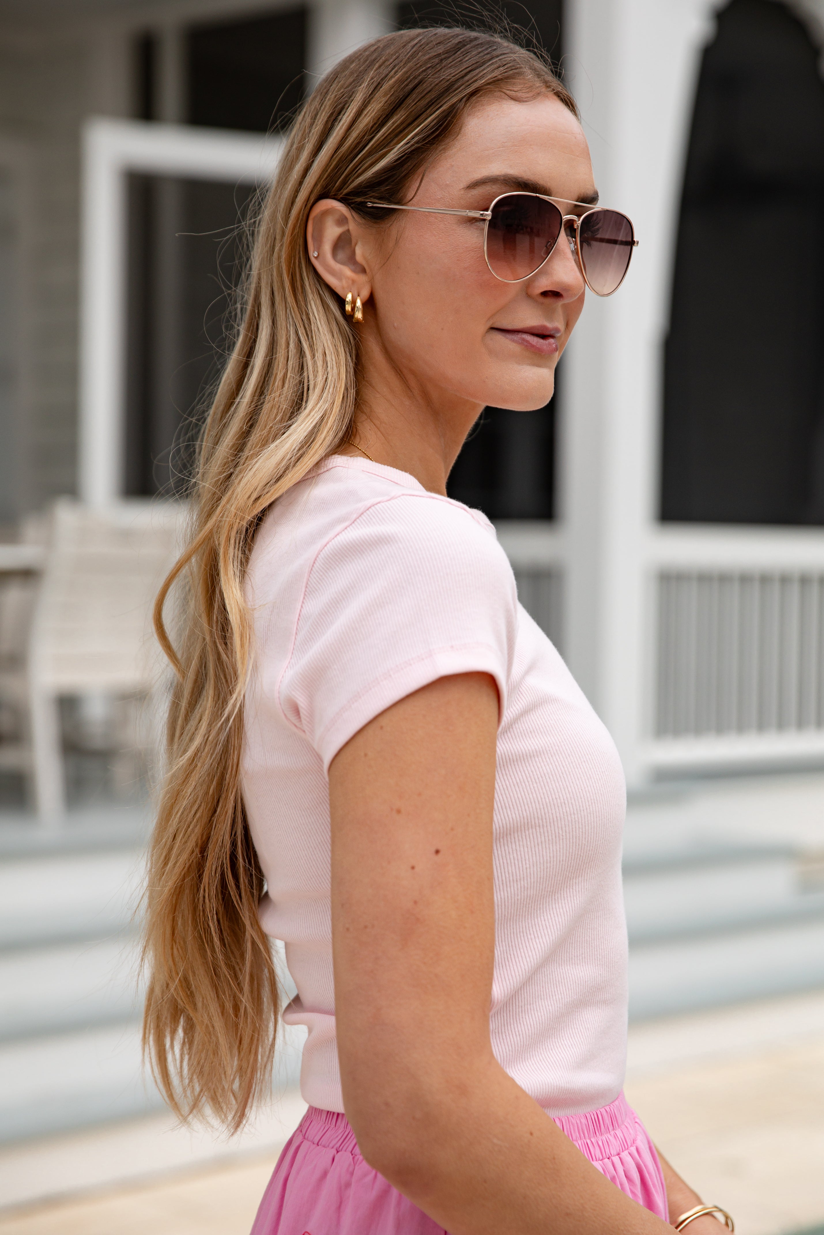 Woman wearing sunglasses and a pink outfit outdoors