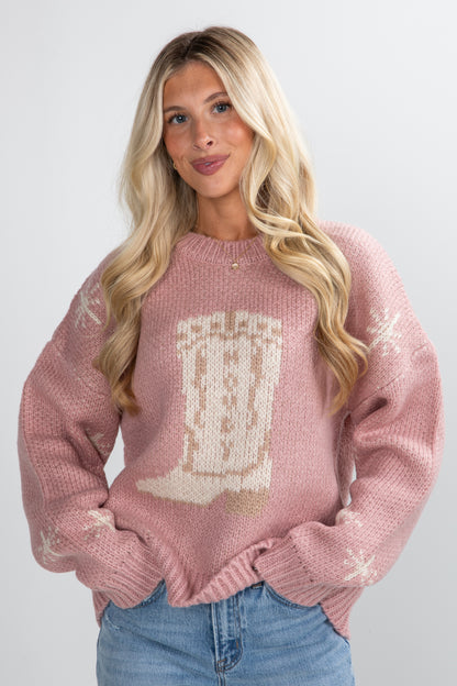 Woman wearing a pink sweater with a graphic design on a plain background