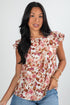 Woman wearing a floral top with ruffled sleeves on a white background