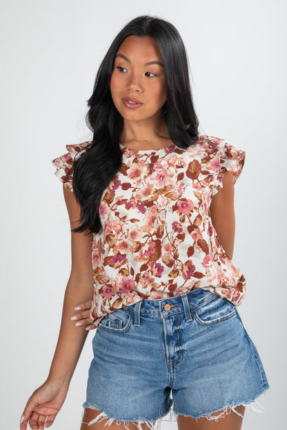 Woman wearing a floral top and denim shorts on a white background