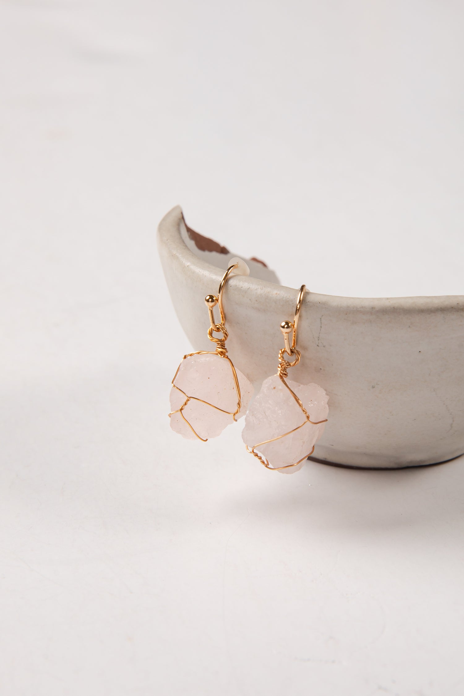 Pink stone earrings with gold wire wrapping on a white background