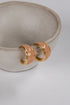 Pair of peach-colored hoop earrings with gold accents on a light gray background