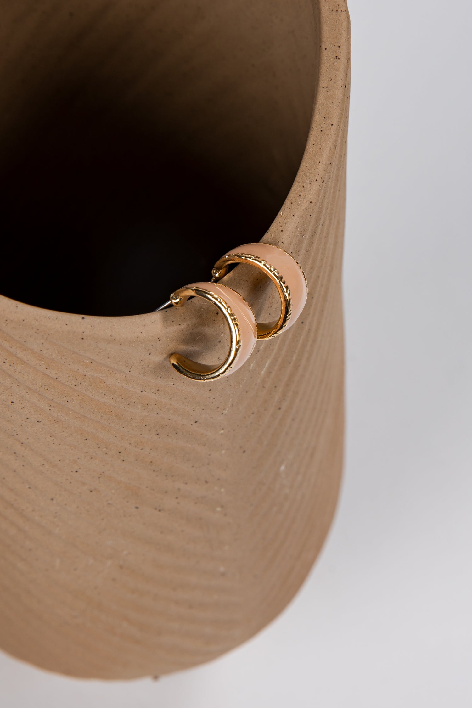 Close-up of a beige woven basket with a gold ring detail on a white background