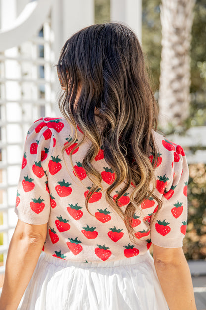Woman wearing a strawberry patterned top with a blurred outdoor background