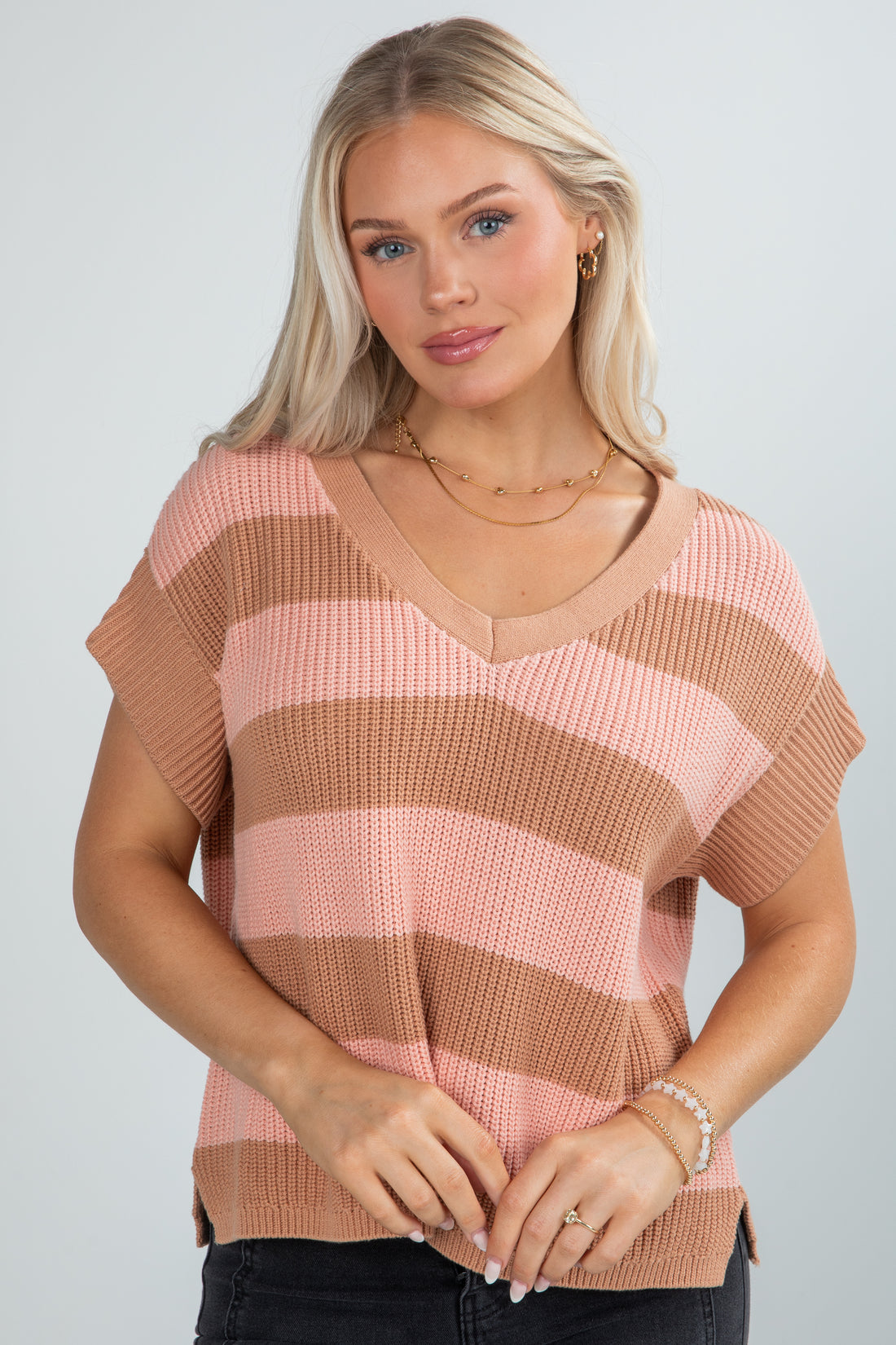 Woman wearing a pink and brown striped sweater against a plain background
