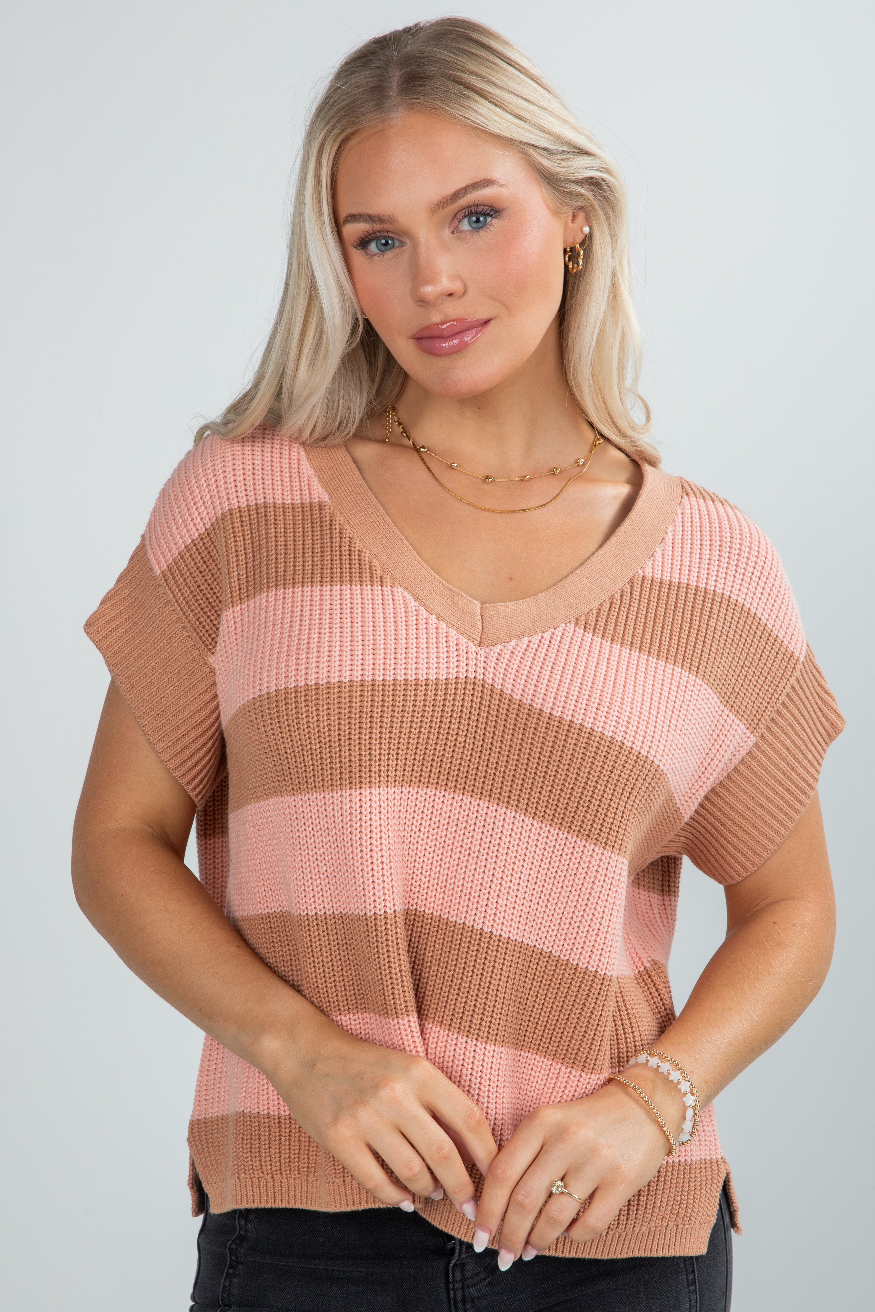 Woman wearing a pink and brown striped sweater against a plain background