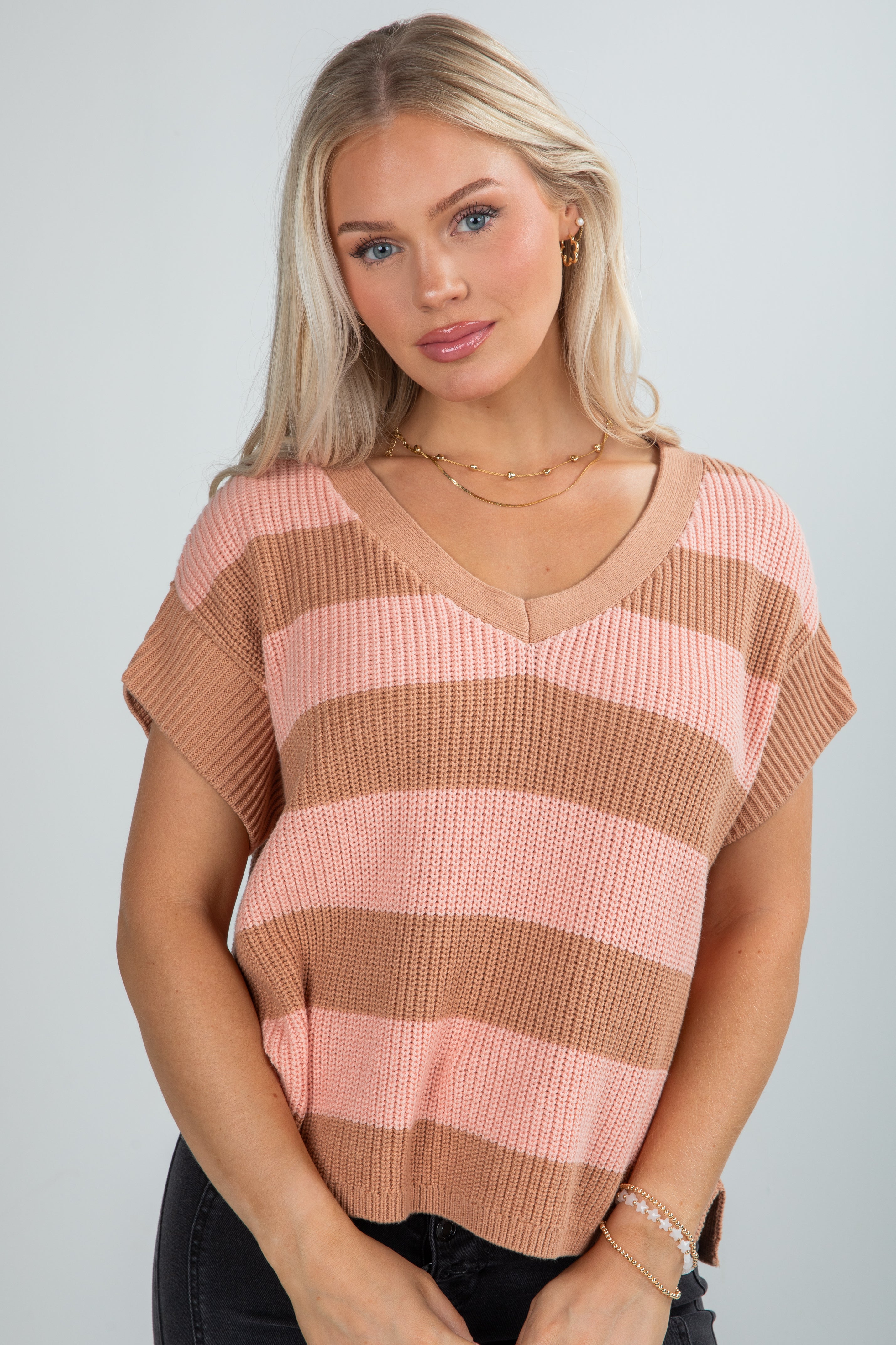 Woman wearing a pink and brown striped sweater against a plain background