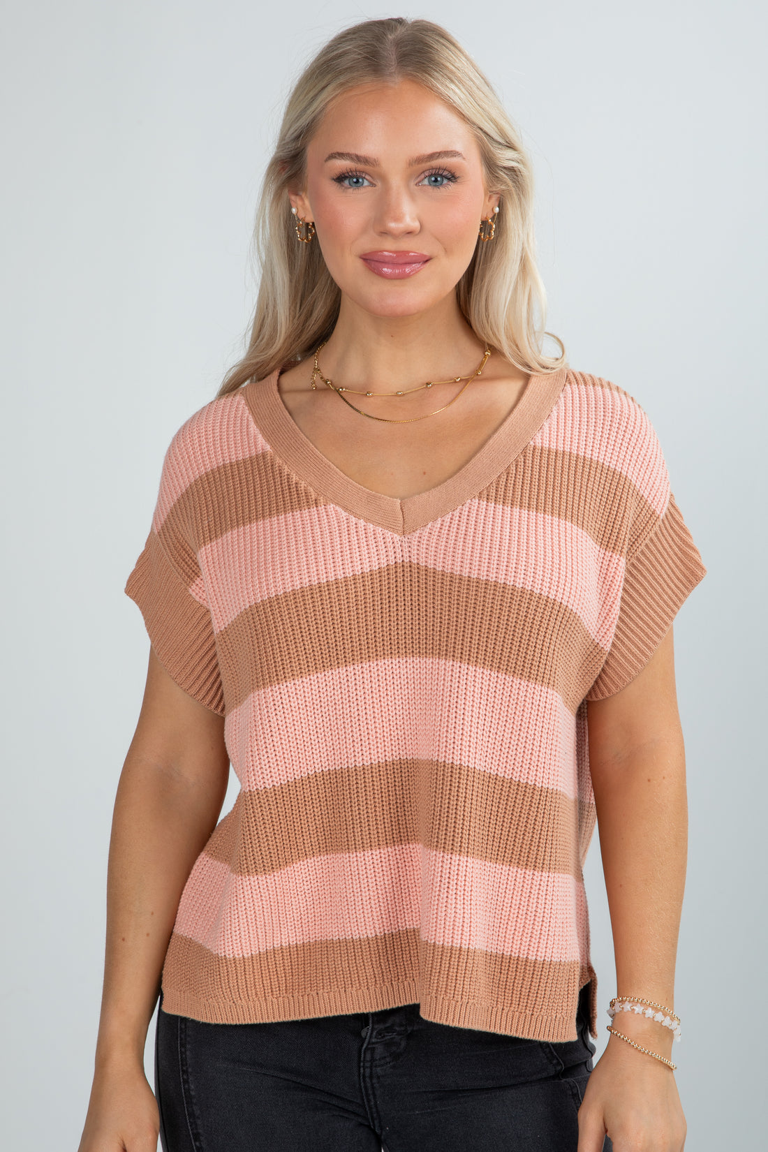 Woman wearing a pink and brown striped sweater against a plain background