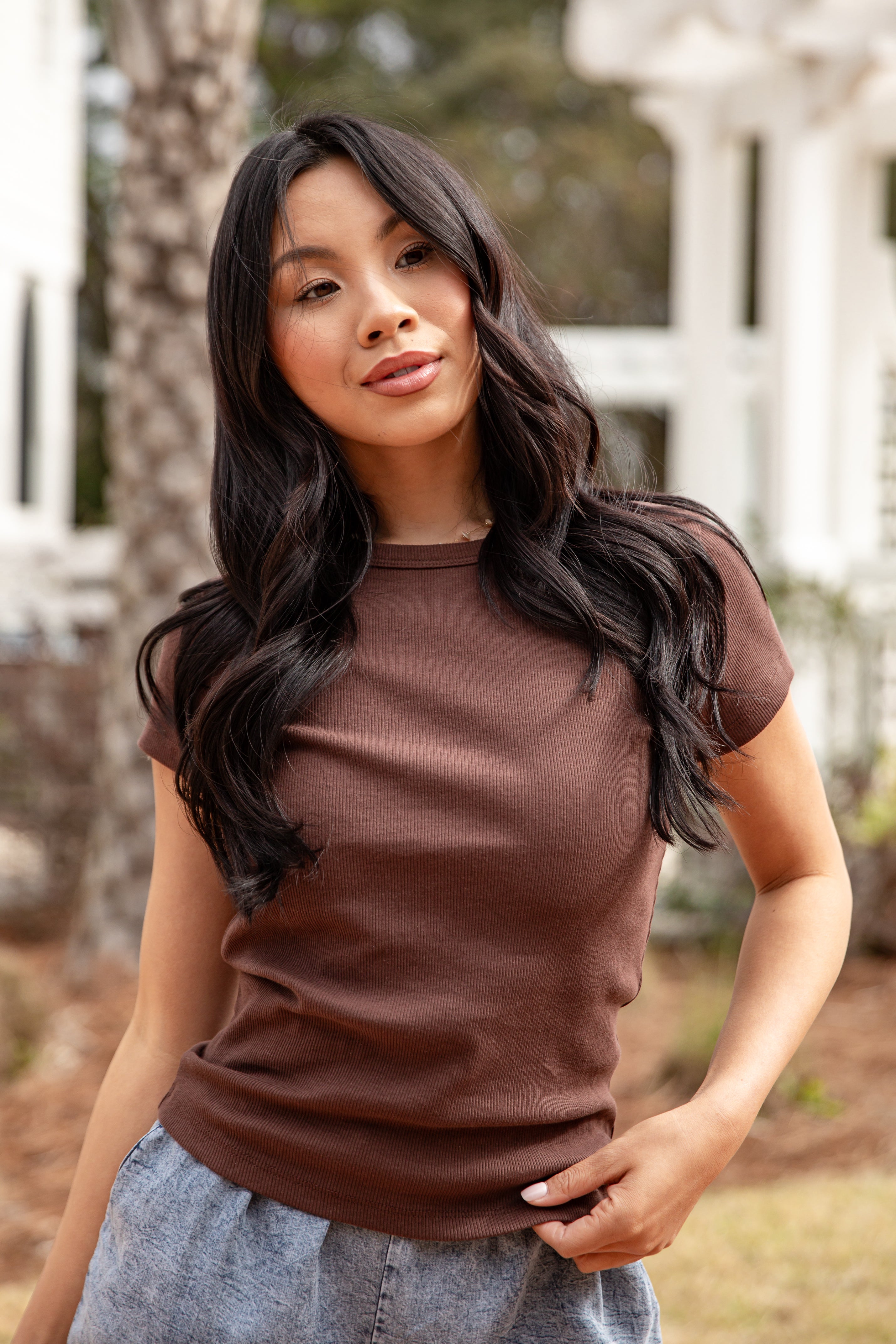 Woman wearing a brown shirt outdoors with blurred background
