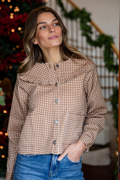 Woman wearing a plaid shirt with a Christmas tree in the background