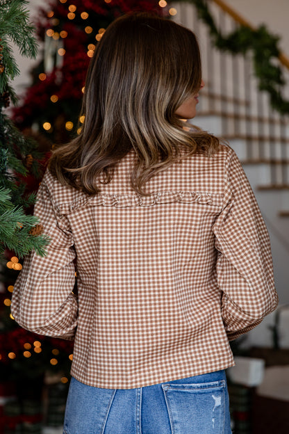 Person wearing a brown checkered shirt in front of a decorated Christmas tree.