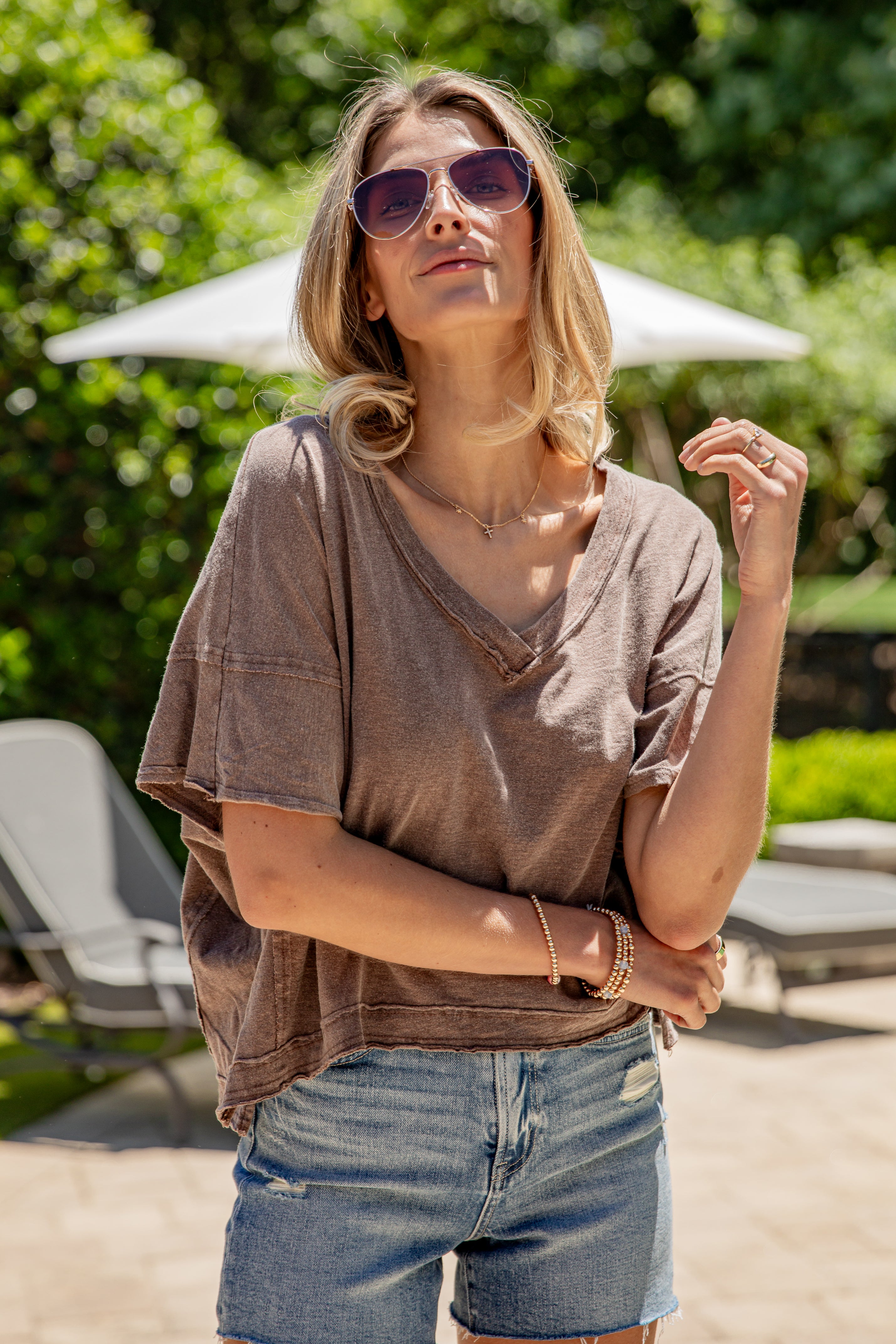 Woman wearing a brown oversized shirt and denim shorts outdoors.