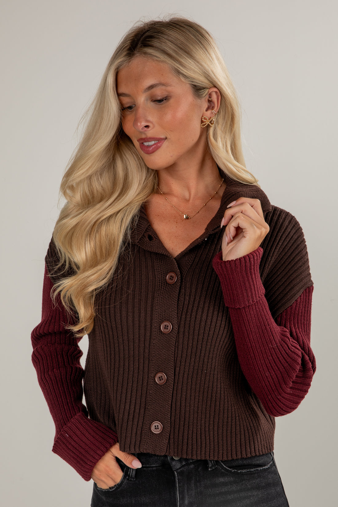 Woman wearing a brown and burgundy ribbed cardigan against a plain background