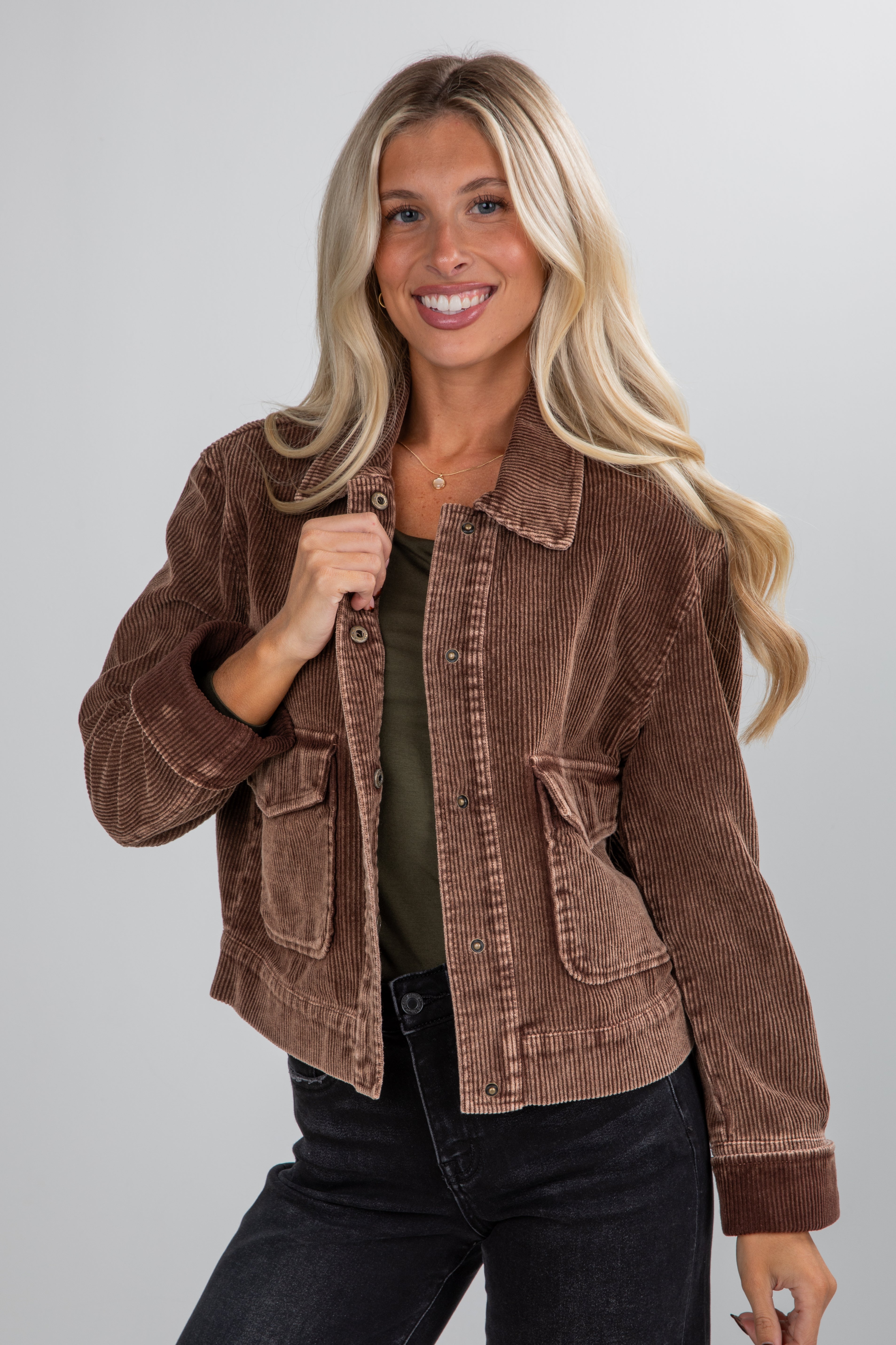 Woman wearing a brown corduroy jacket on a plain background