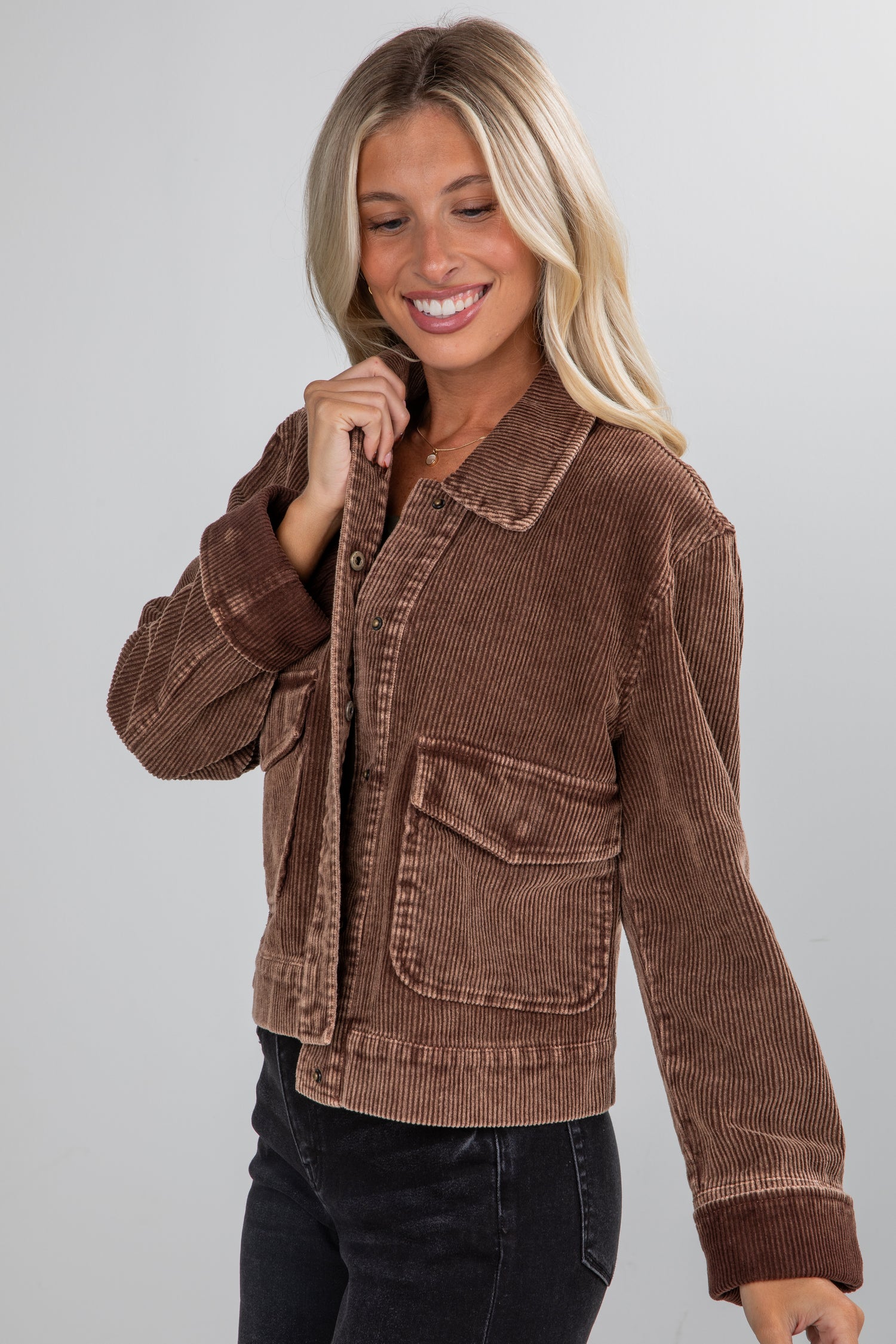 Woman wearing a brown corduroy jacket on a gray background