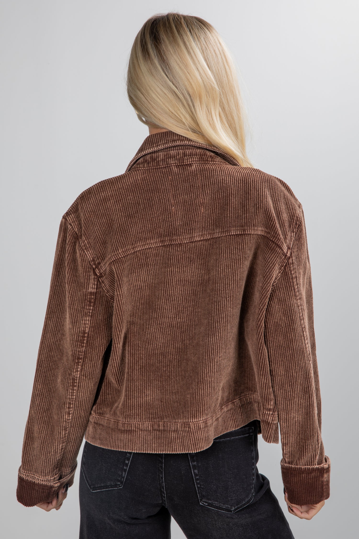 Person wearing a brown corduroy jacket on a plain background