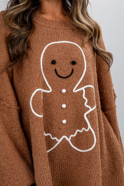 Brown sweater with a gingerbread man design on a plain background