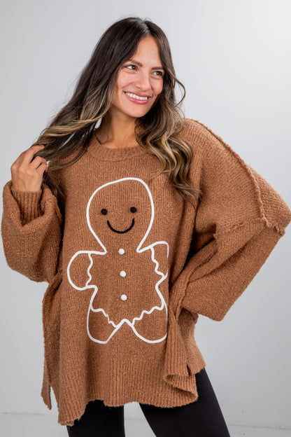 Woman wearing a brown sweater with a gingerbread man design against a white background