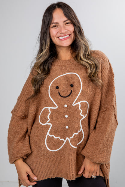 Woman wearing a brown sweater with a gingerbread man design against a white background