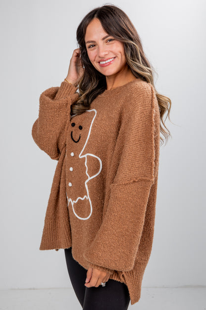 Woman wearing a brown sweater with a gingerbread man design on a white background