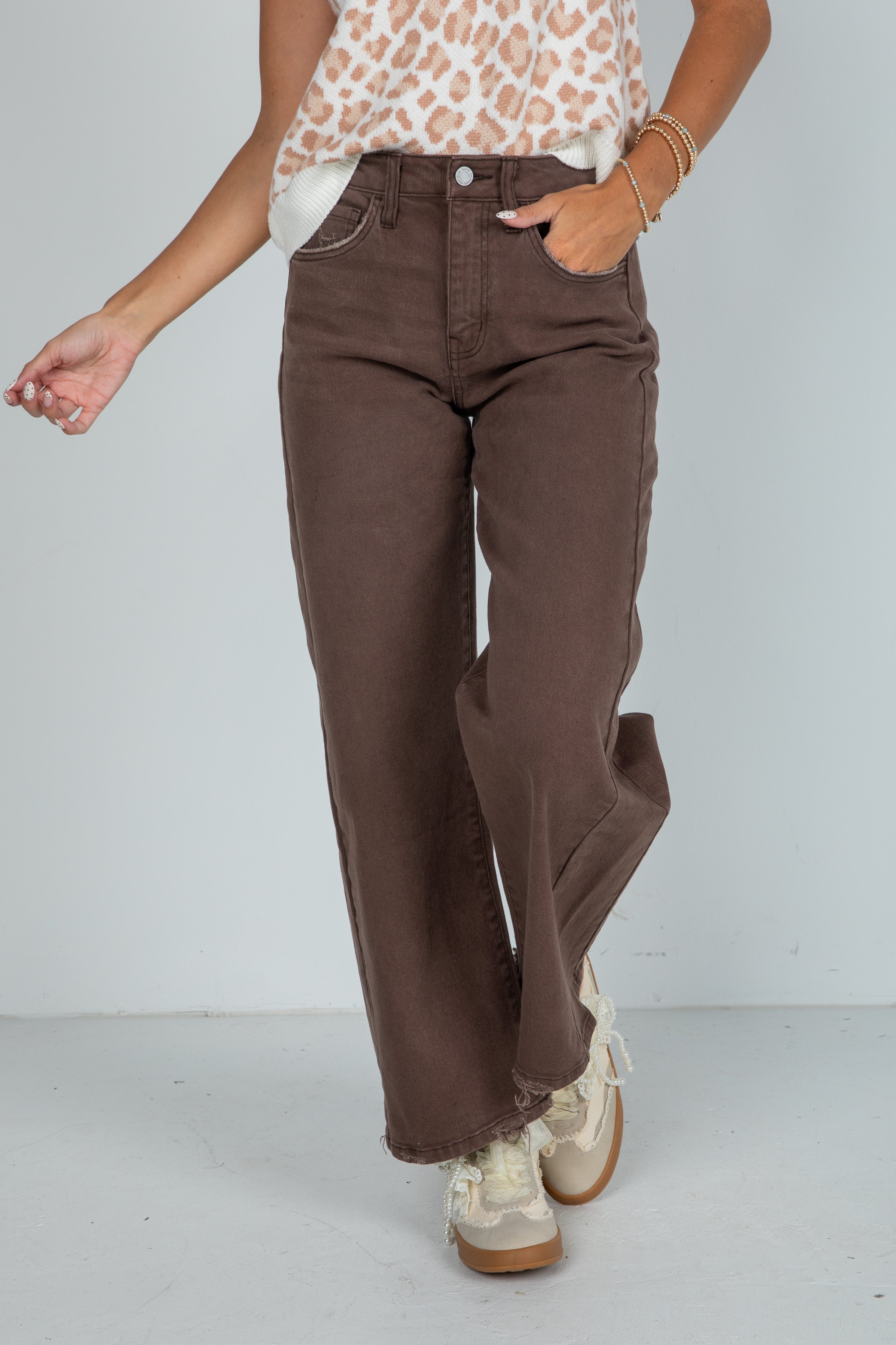 Person wearing brown wide-leg jeans with a plain background