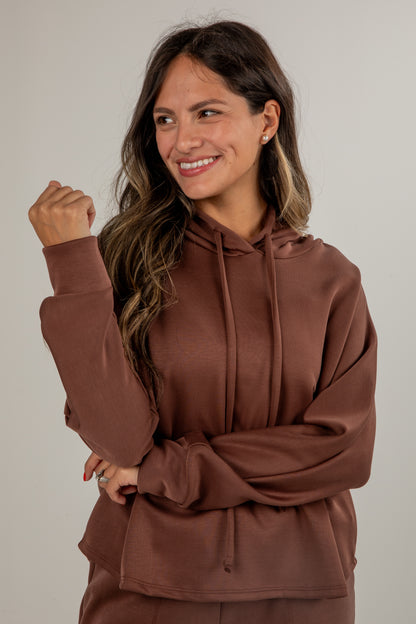 Woman wearing a brown hoodie against a plain background
