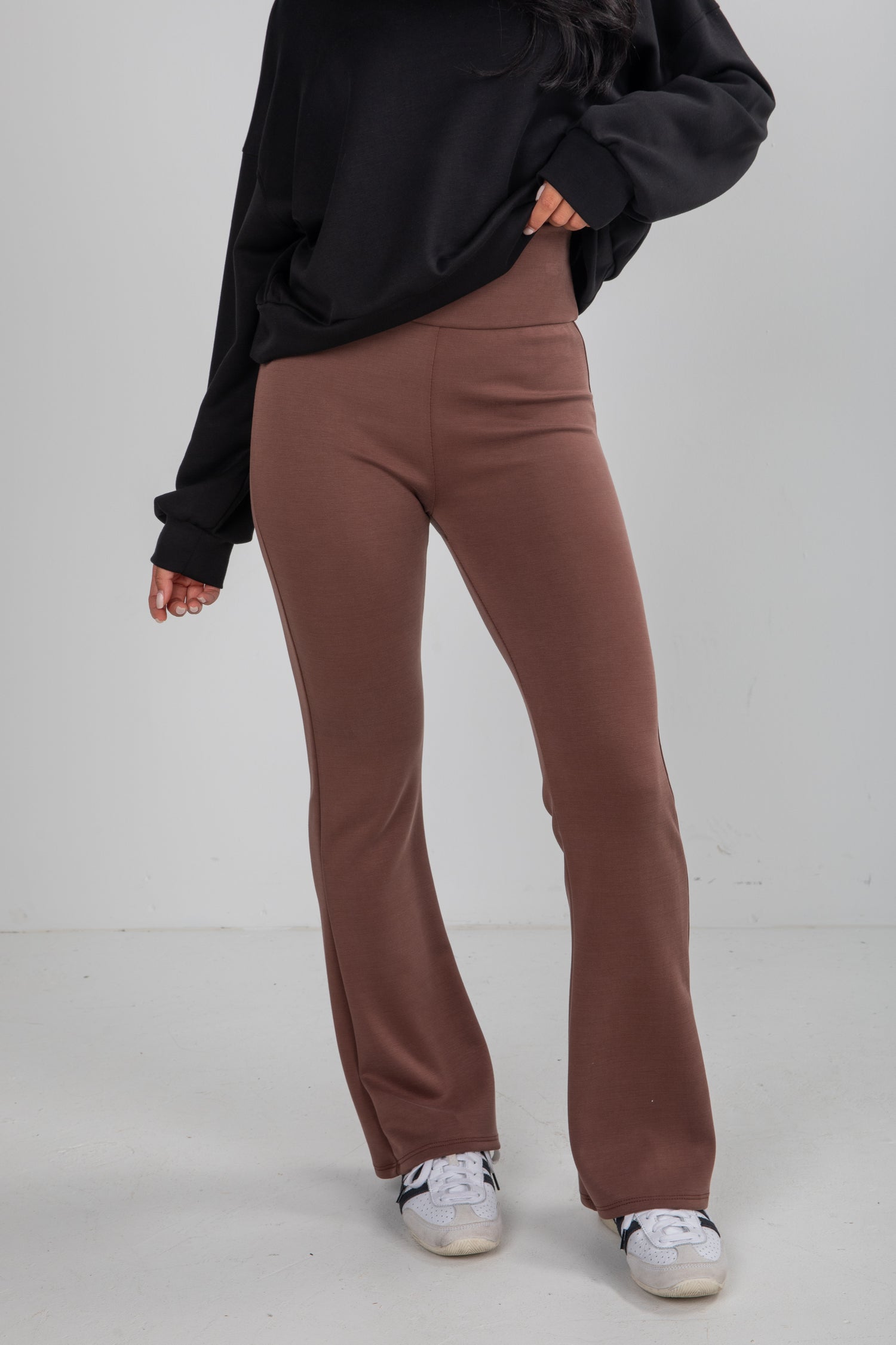 Person wearing brown pants and a black top on a white background