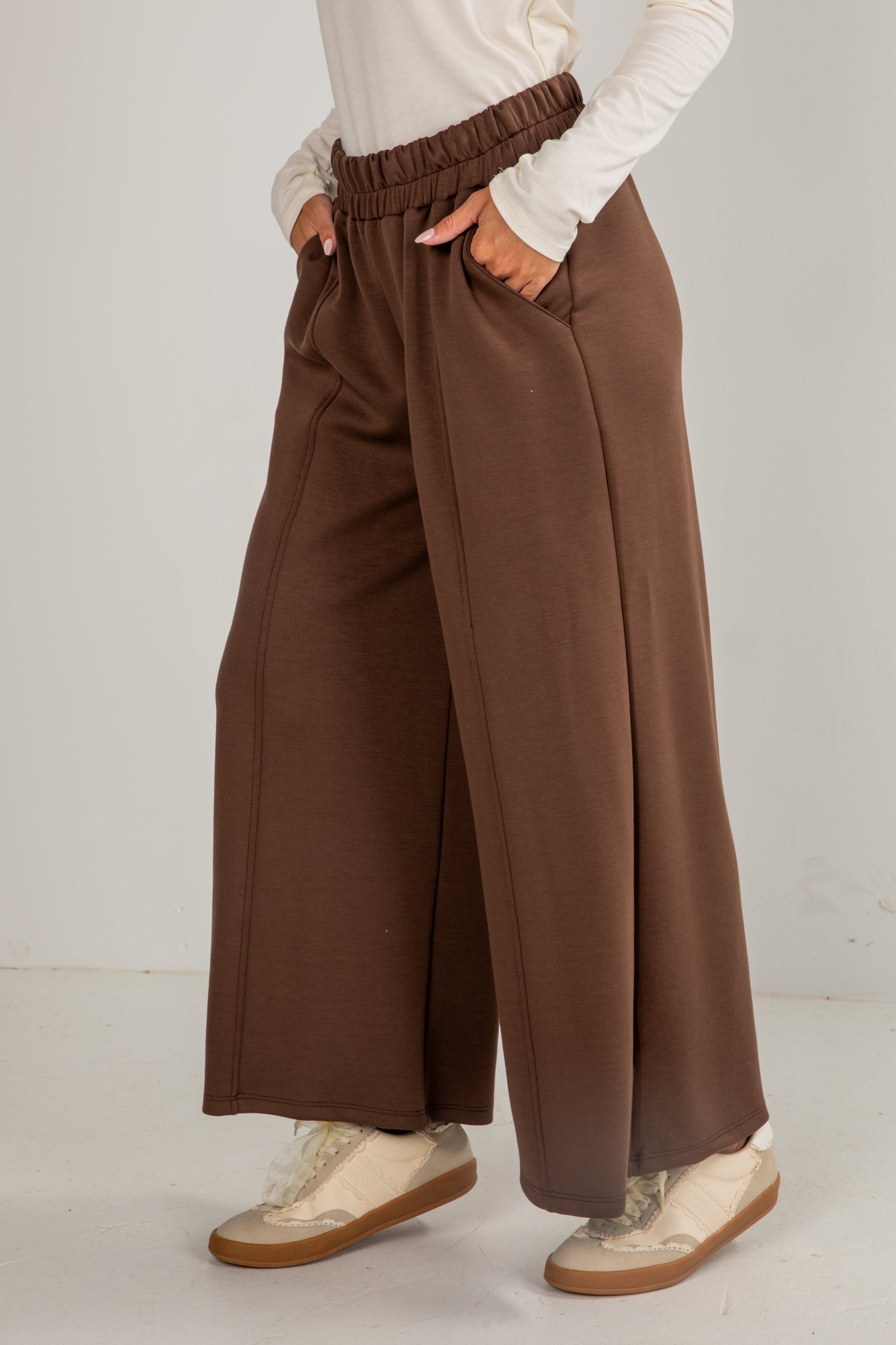 Person wearing brown wide-leg pants with a plain background