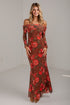 A woman modeling an off-the-shoulder long-sleeve maxi dress with a rust brown base and a red floral pattern, standing in a plain studio setting.