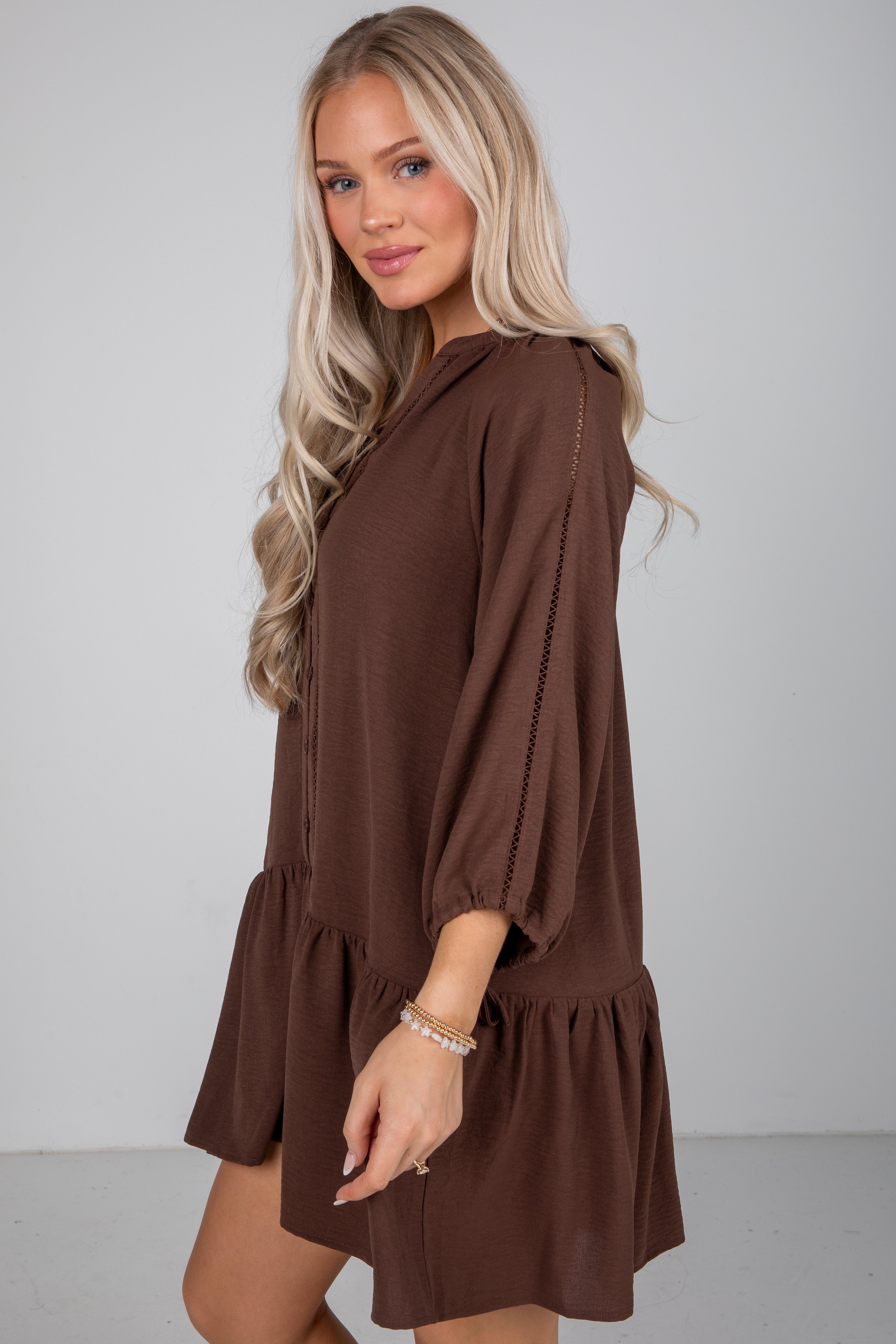 Woman wearing a brown dress against a plain background