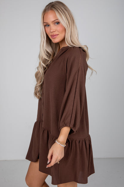 Woman wearing a brown dress against a plain background