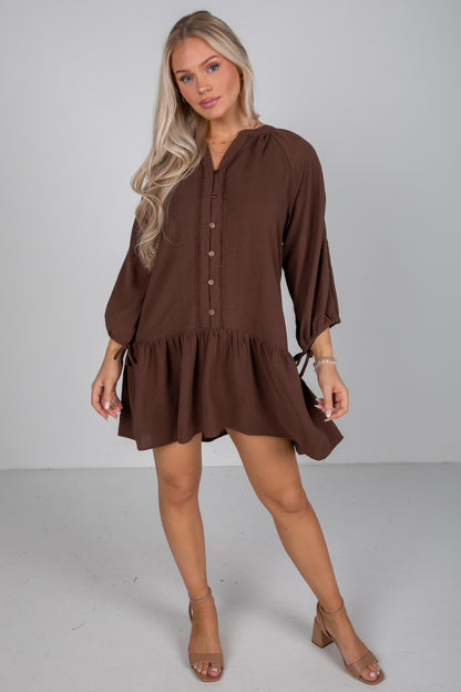 Woman wearing a brown dress against a plain background