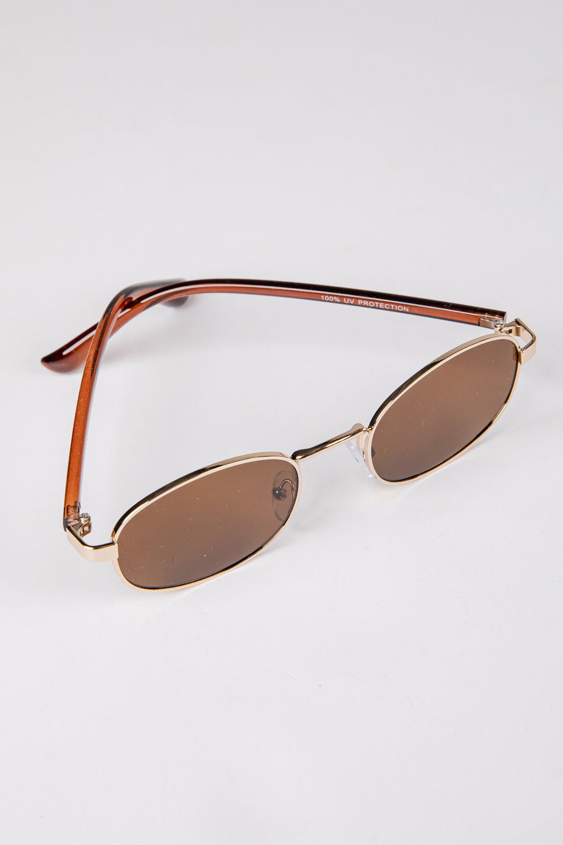 Gold-framed sunglasses with brown lenses on a white background