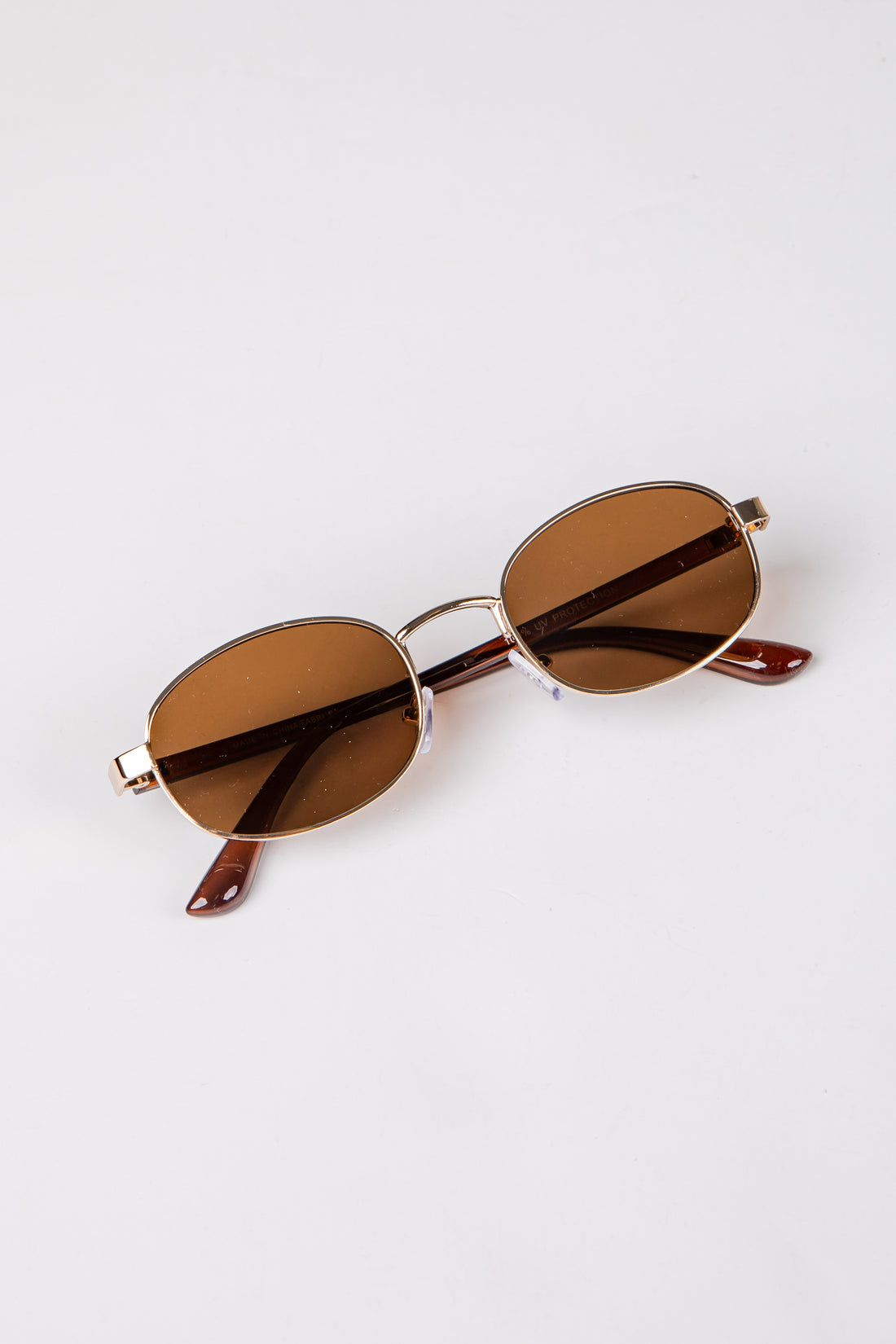 Sunglasses with brown lenses and gold frame on a white background
