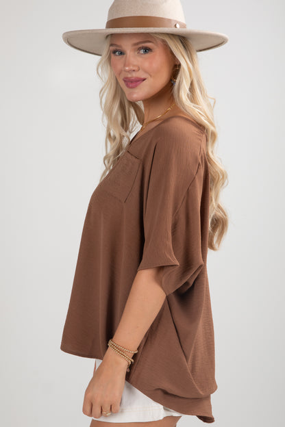 Woman wearing a brown top and beige hat on a white background