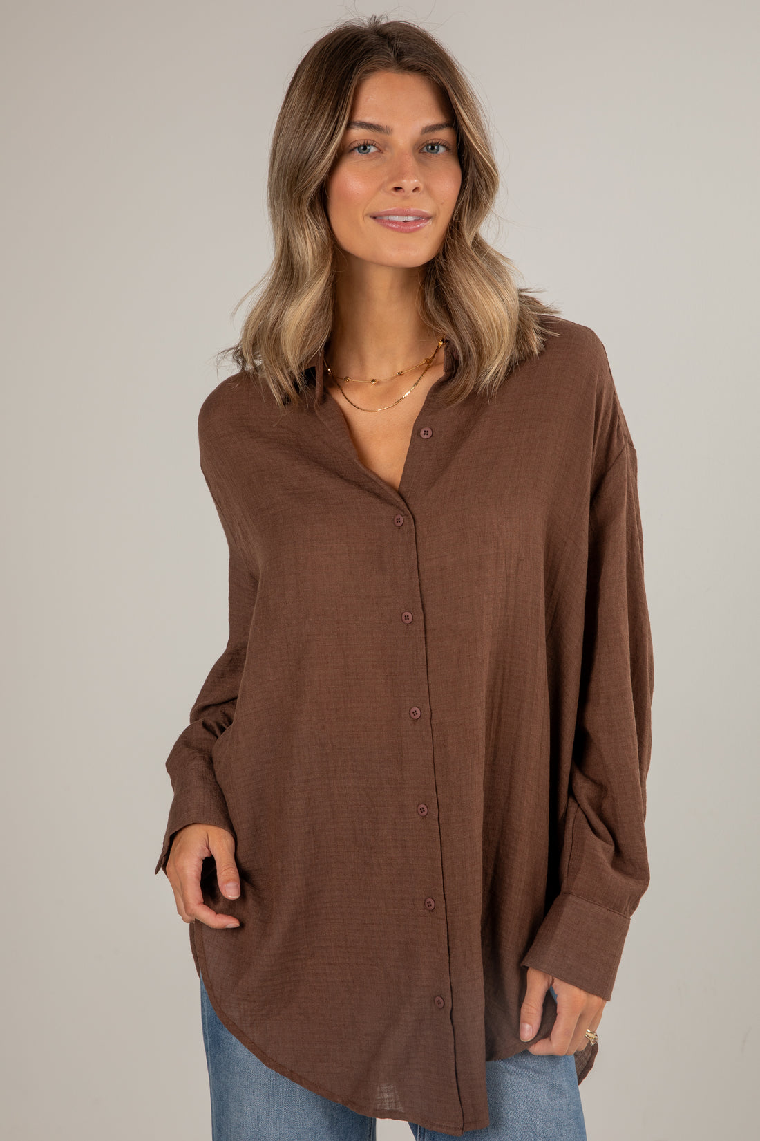 Woman wearing a brown button-up shirt against a plain background