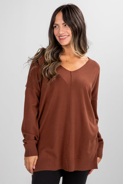 Woman wearing a brown sweater against a plain background