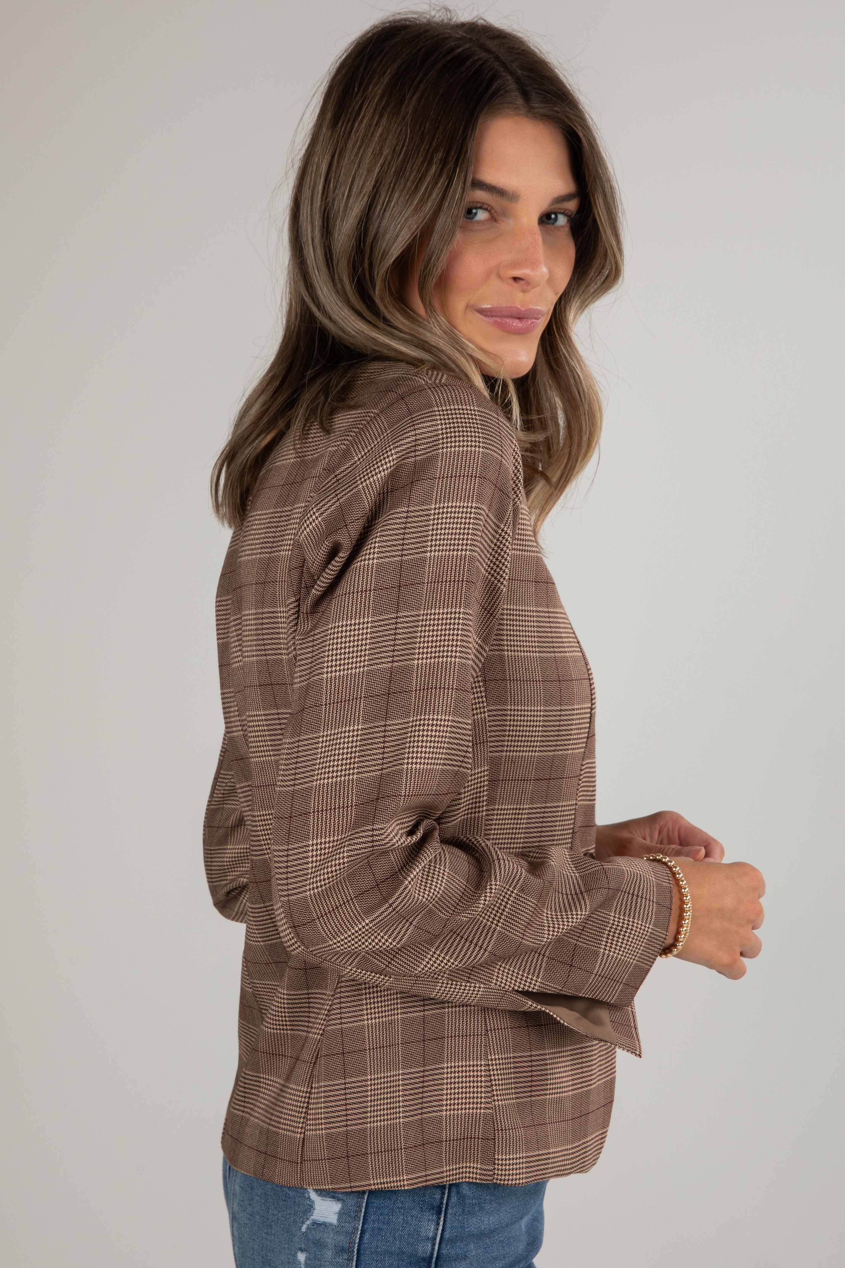 Woman wearing a brown plaid shirt against a plain background
