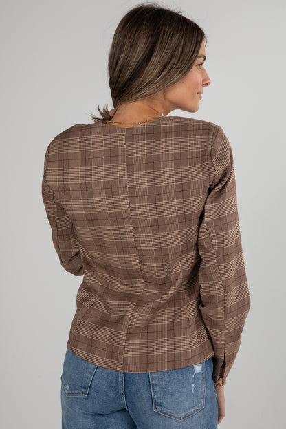 Woman wearing a brown plaid shirt and blue jeans on a plain background