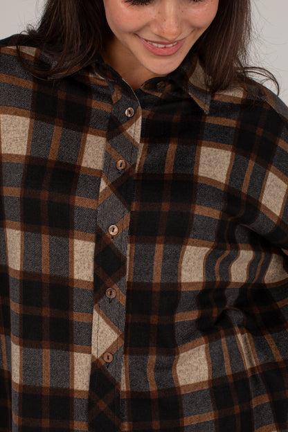 Close-up of a woman wearing a plaid button-up shirt in dark brown, black, and beige tones.