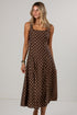A woman modeling a brown sleeveless midi dress with a white polka dot pattern against a plain light gray studio background.