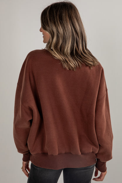 Person wearing a brown sweater against a plain background