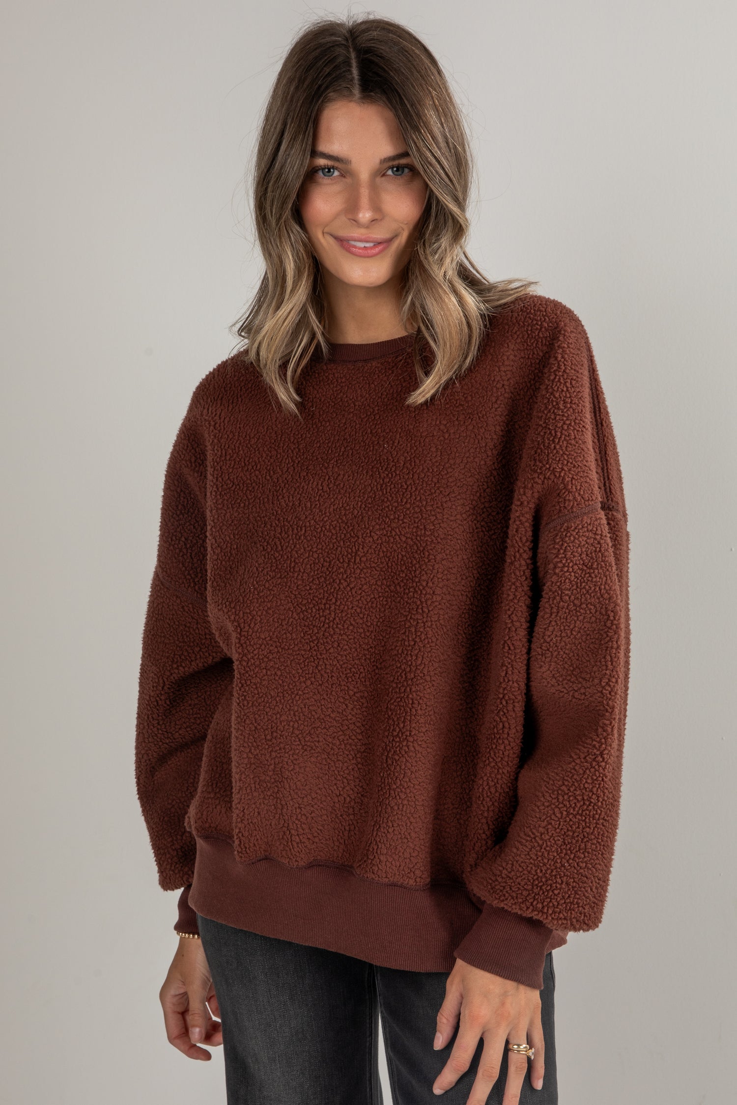 Woman wearing a brown sweater against a plain background